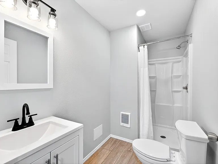 Full bathroom with a vanity, framed mirror, and a tub/shower combo with built-in shelving for everyday storage.