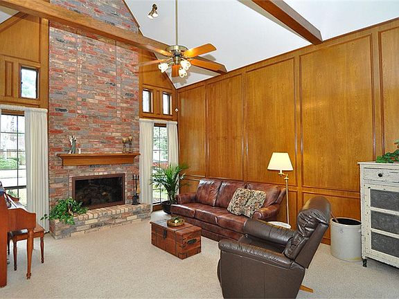 The awesome family room has a cathedral ceiling, wood beams, and a gorgeous soaring brick fireplace.