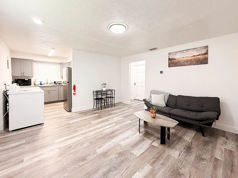 Open living area with seating and cafe table, connected to a functional kitchen with ample cabinetry and full-size fridge.