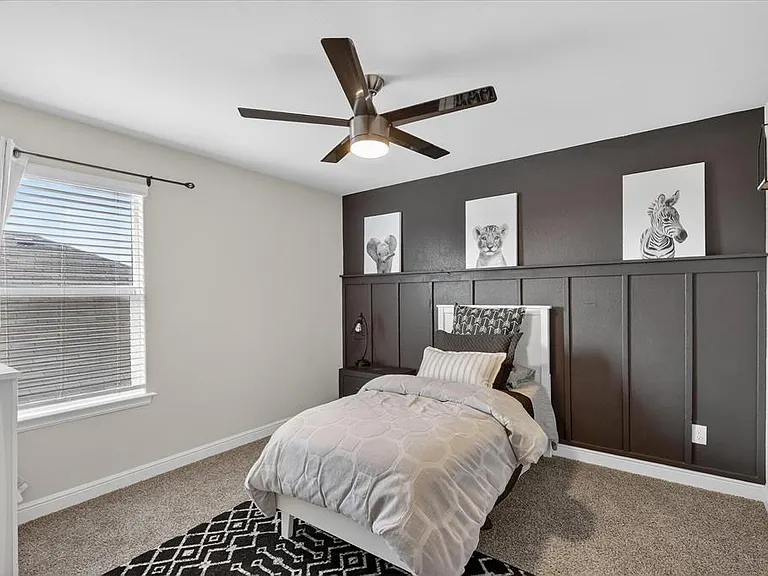 Bedroom featuring a decorative accent wall with paneling, a ceiling fan with integrated lighting, and a single window with blinds