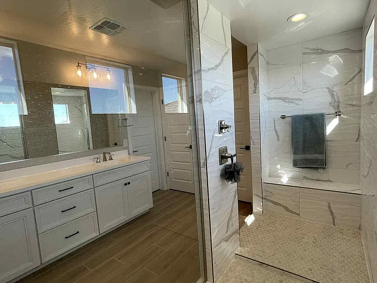 Primary shower with 2 shower heads and sitting area.