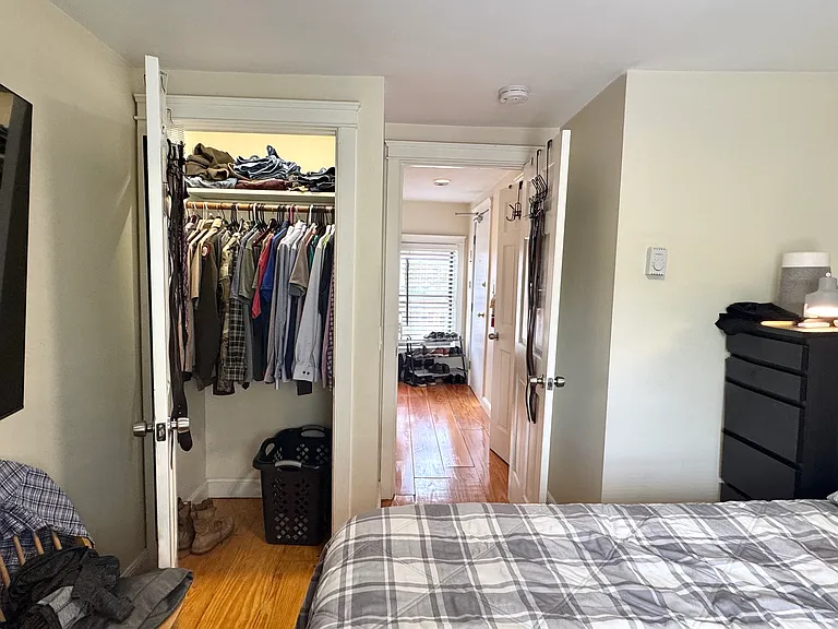 Furnished bedroom with queen bed, two dressers, wall-mounted flat-screen TV, and closet.