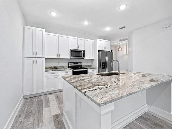 Kitchen offering shaker style cabinetry, brand new appliances, solid surface granite counter tops with an over sized island allowing for tuck under seating.