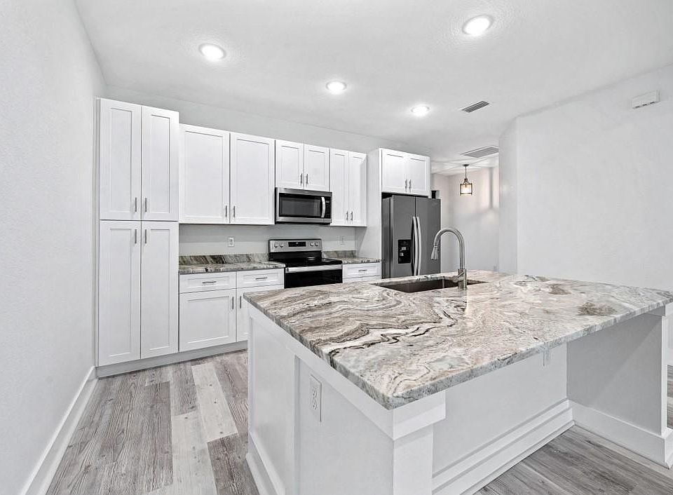 Kitchen offering shaker style cabinetry, brand new appliances, solid surface granite counter tops with an over sized island allowing for tuck under seating.