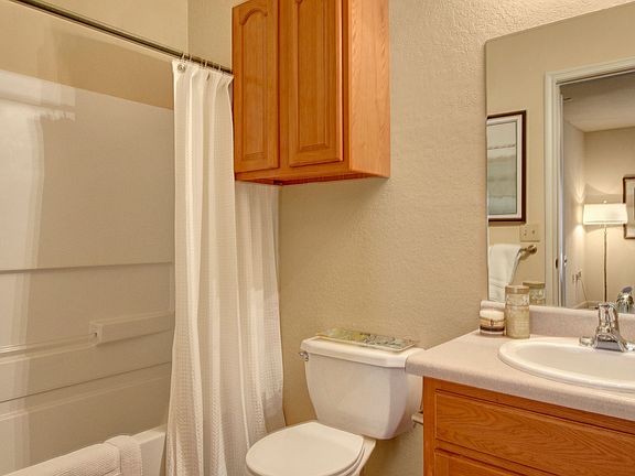 A bathroom with a tub, wall storage, and wide mirror over the sink