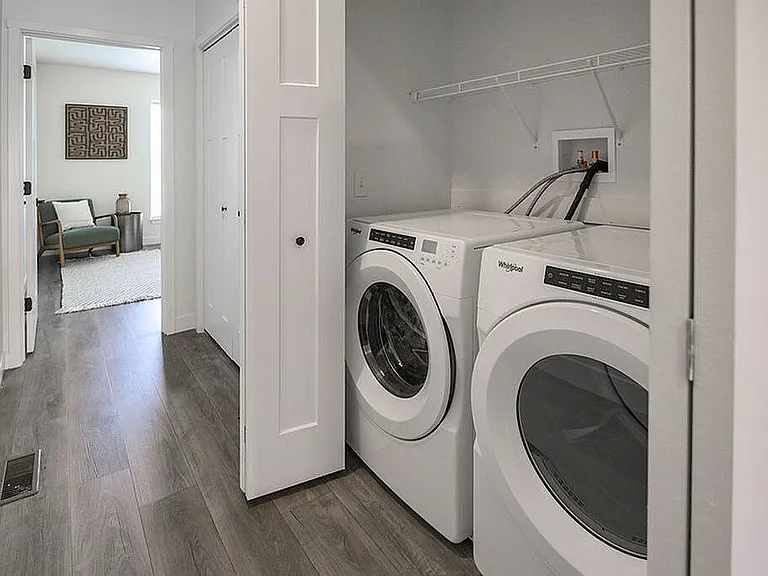 Modern apartment with sleek laundry area, featuring washer and dryer adjacent to a cozy seating nook with natural light.