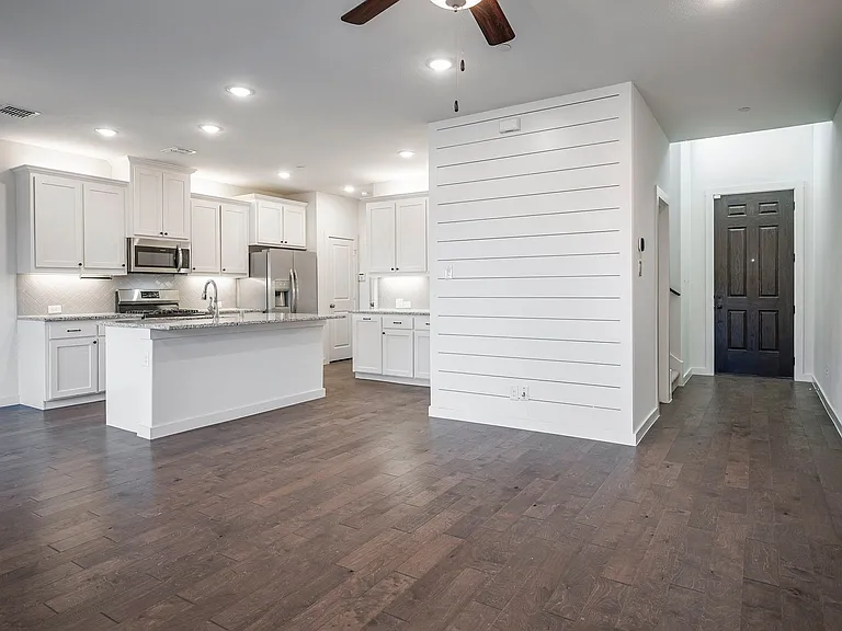Gorgeous kitchen with stainless steel appliances, dark wood-style floors, a kitchen island with sink, and recessed lighting.