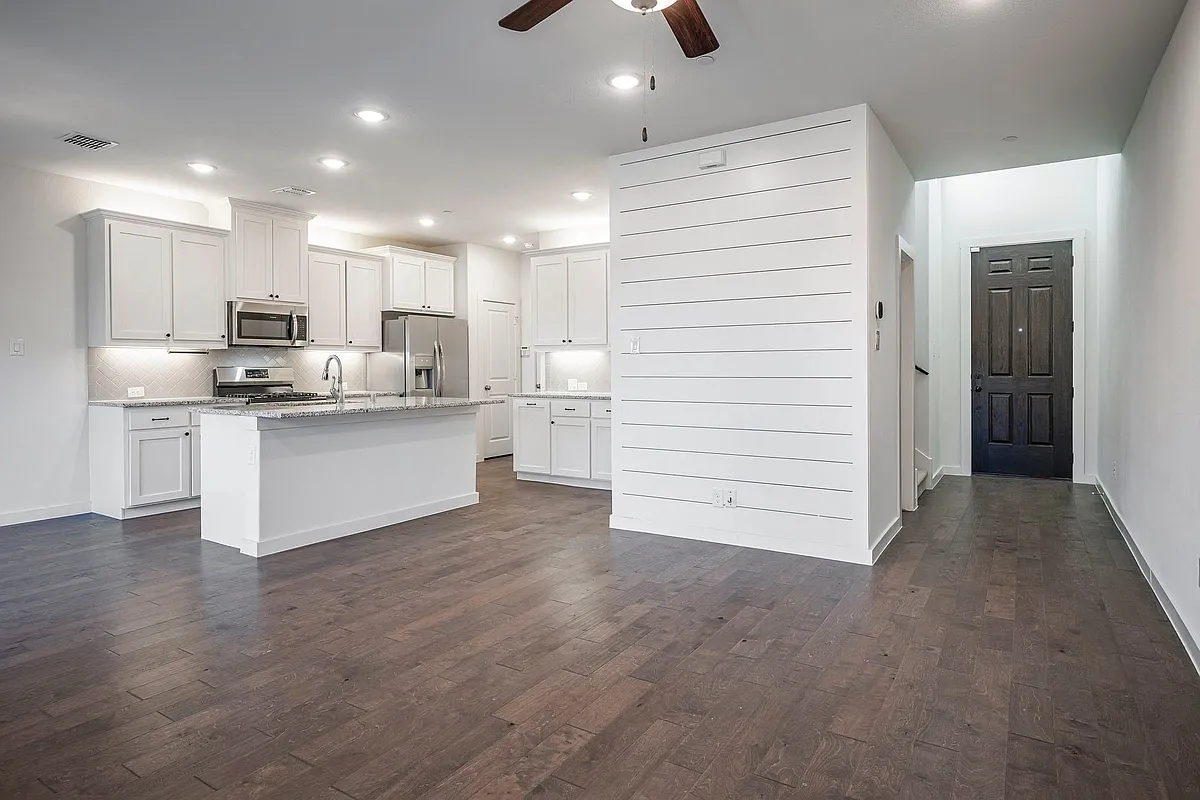 Gorgeous kitchen with stainless steel appliances, dark wood-style floors, a kitchen island with sink, and recessed lighting. - 2971 Stunning Dr