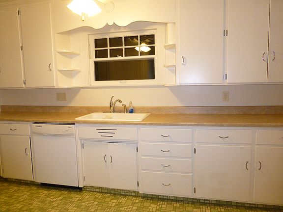 View of dishwasher, sink and many cabinets.