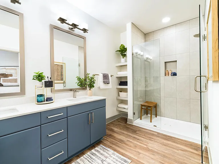 A refined primary bath with a glass-enclosed shower, open shelving, and clean-lined finishes that support a calm, everyday routine.