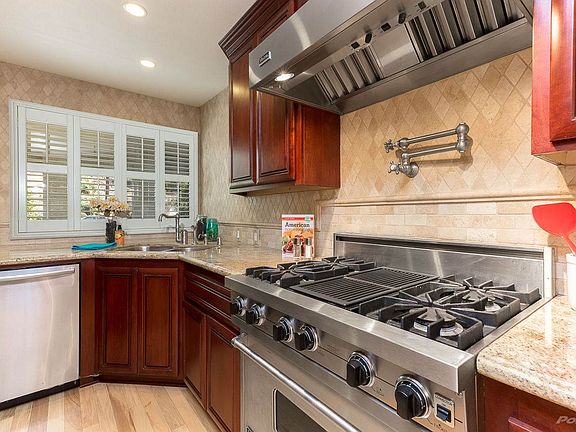 The large entertainer's kitchen offers premium cherry wood cabinets, granite countertops, stainless steel appliances that include a commercial grade stove with a pot filler, travertine tile backsplash & much more!