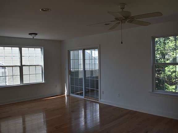 Living area with large windows and ceiling fan.