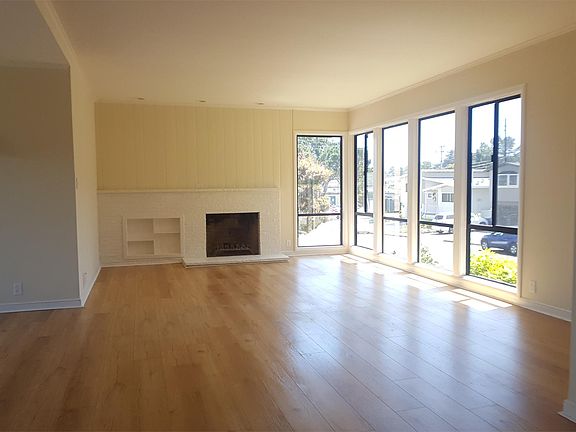 Spacious light filled living area with wooden floors and fireplace.