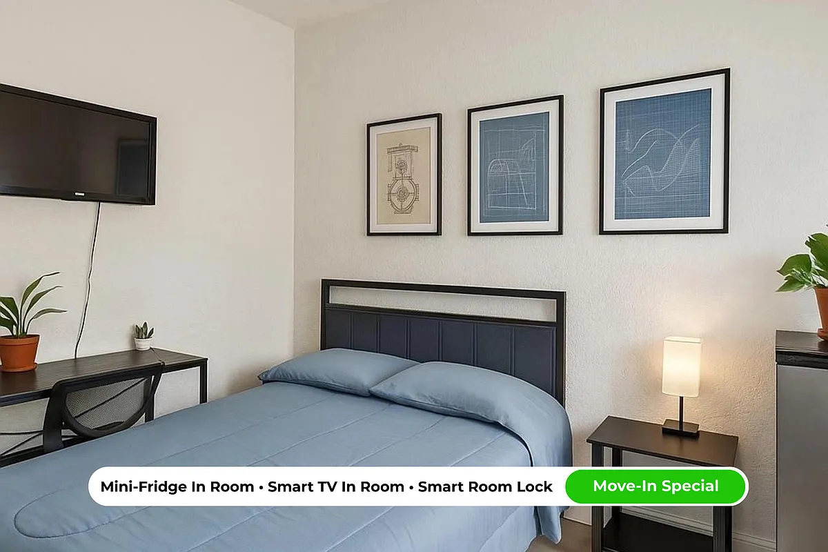 Light-filled queen room featuring a work desk + chair, Smart TV, mini fridge, and central A/C for everyday comfort. - 15th St S