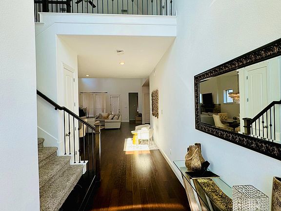 Entrance with high ceiling, warm wood floor and wrought iron railing