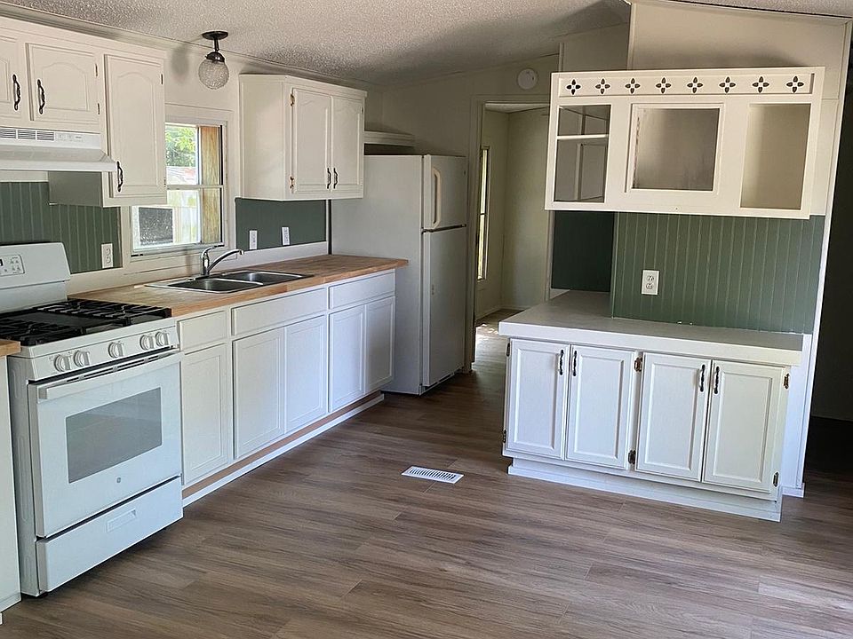 Large Kitchen with white Stove and Refrigerator. Newly painted cabinets. New butcher block counter