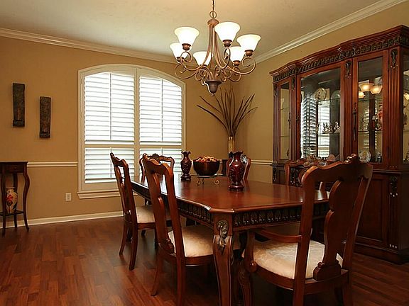 JUST OFF THE FOYER...THE BANQUET SIZED DINING ROOM SHOWCASES TRENDY LIGHTING, CROWN MOLDING, CHAIR RAILING, AND PLANTATION SHUTTERS.