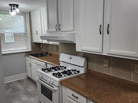 One side of the kitchen with brand new tile floor, double wide sink, stove, dishwasher, lots of cabinet space.