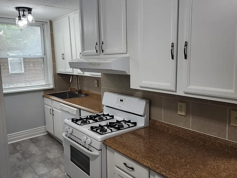 One side of the kitchen with brand new tile floor, double wide sink, stove, dishwasher, lots of cabinet space.
