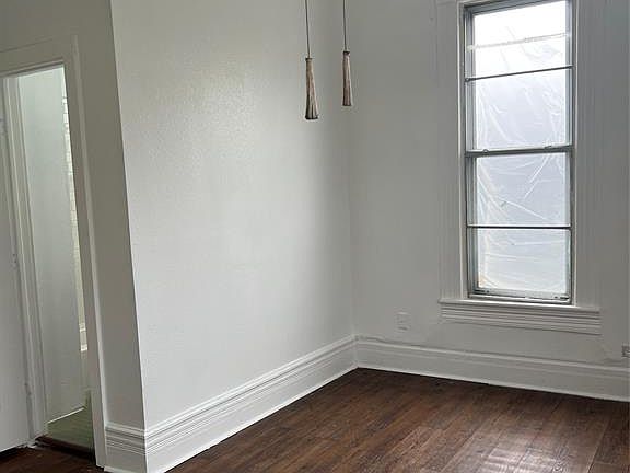 Empty room featuring dark wood finished floors and baseboards
