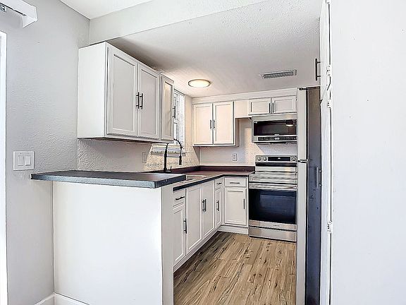 Modern kitchen with sleek white cabinetry, stainless steel appliances, and elegant wood flooring, offering a stylish and functional cooking space.