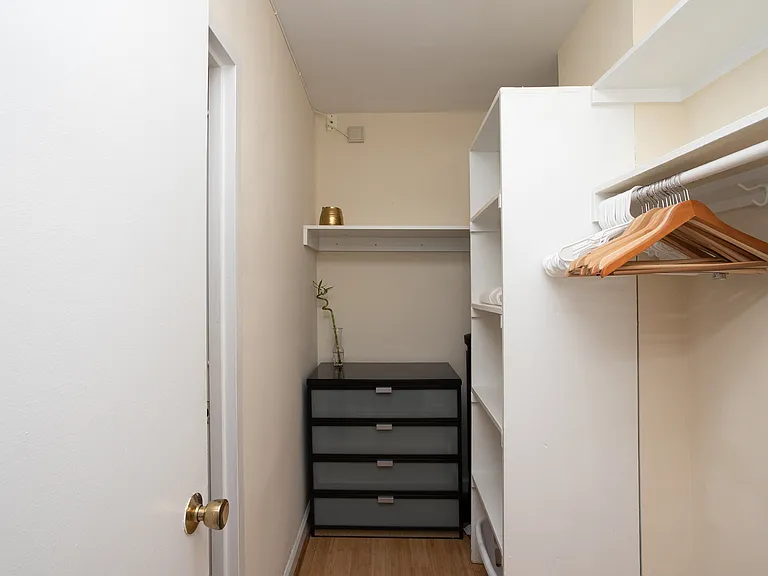 The walk-in closet features built-in shelves and plenty of storage room.