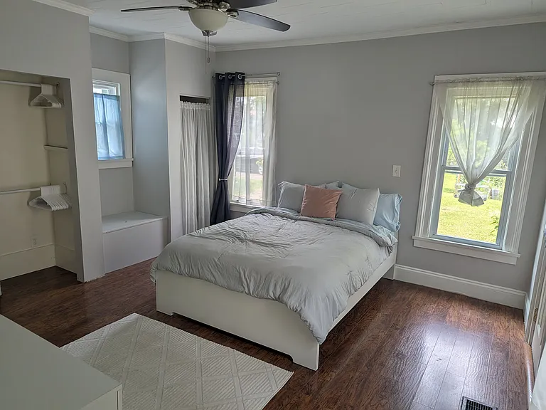 From the living room. Back bedroom facing the backyard. Exit door to the right and closets on the left.