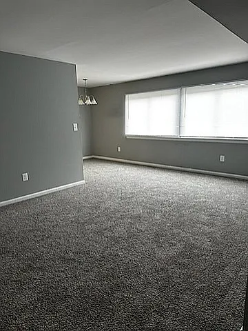 Experience comfort and elegance in this spacious carpeted living room, perfect for relaxation.