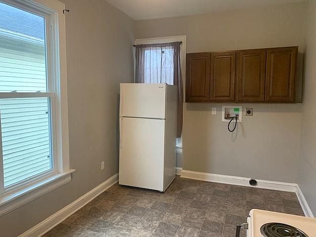 Other half of kitchen, with windows, fridge, and washer/dryer hook up.