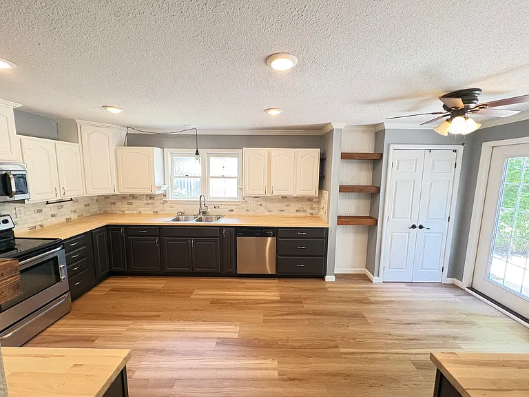 The extra-large kitchen boasts butcher-block countertops, marble backsplash, abundant storage, and French doors opening to the back patio, creating an ideal space for cooking, baking, and entertaining.