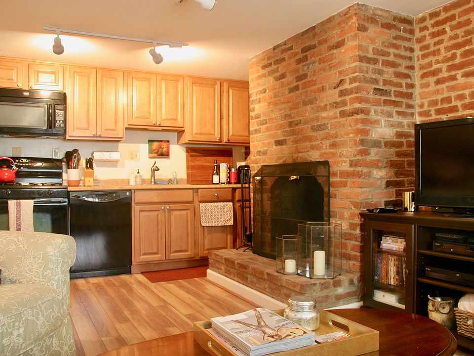 Living room with wood-burning fireplace; kitchen in back