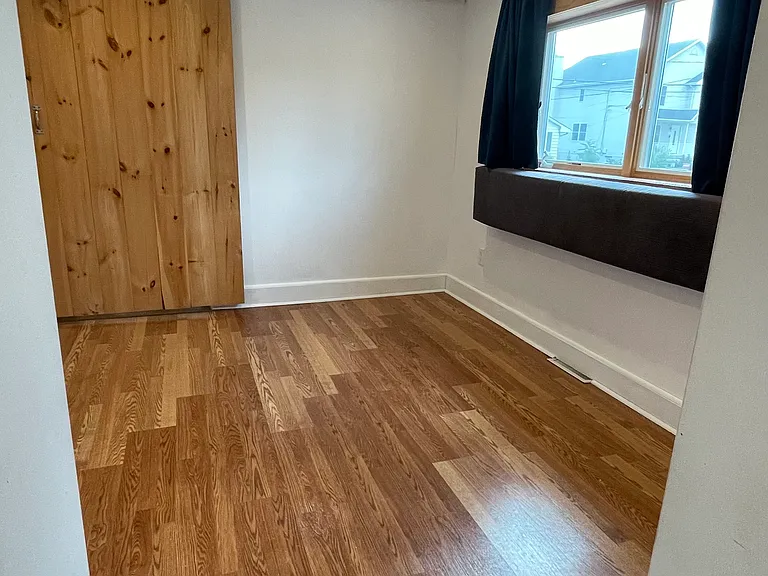 Bright primary bedroom with hardwood floors, ceiling fan, and charming wood barn door detail.