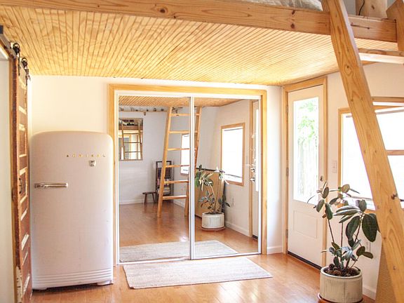 Lofted bedroom space facing laundry area behind mirrored sliding doors, side door to the right.