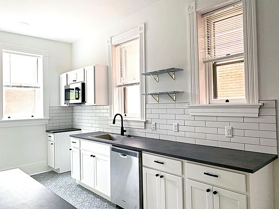 Galley kitchen with beautiful patterned floor tile, marble floating wall shelves, and new appliances. 
*Refrigerator and range have now been installed*