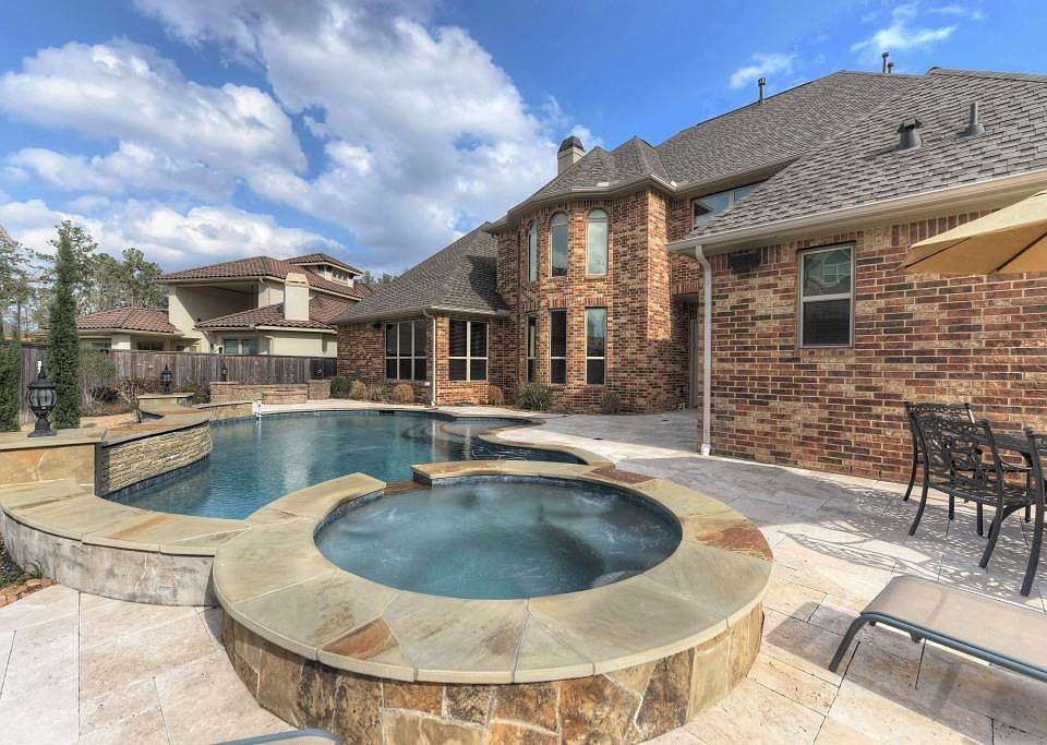 Heated pool & spa with travertine decking + stone gas firepit, exterior lighting, gas grill with granite countertop, outdoor refrigerator, audio system, & mosquito misting system!