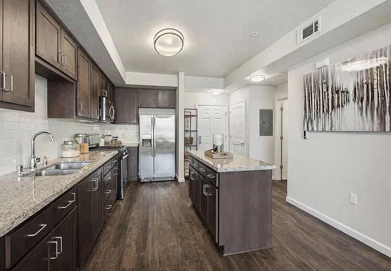 Aspire Apartments Tracy CA A modern kitchen with dark wood cabinets and stainless steel appliances.