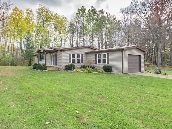 A front view of the home which is surrounded by grassy and wooded areas for quiet seclusion. Home also features newer eaves and downspouts in 2014 along with the metal roof. 