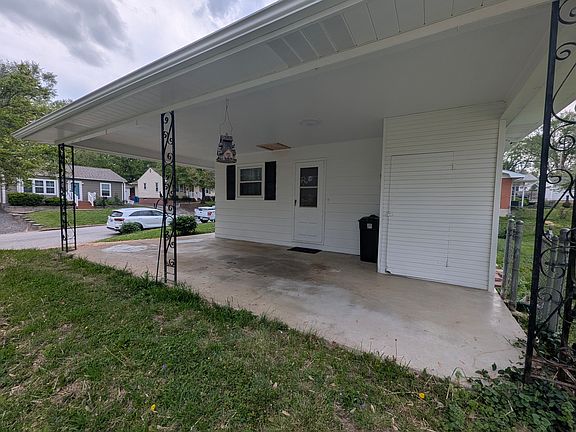 side view of house showing carport, side entrance to house, and built in storage shed