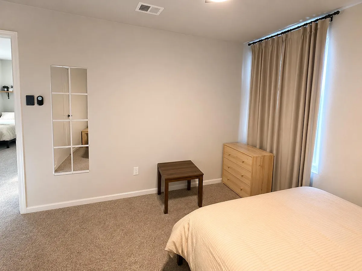 Bedroom offers carpeted flooring, a large window with curtains, and included dresser plus side table for easy storage. - Raphael Cv