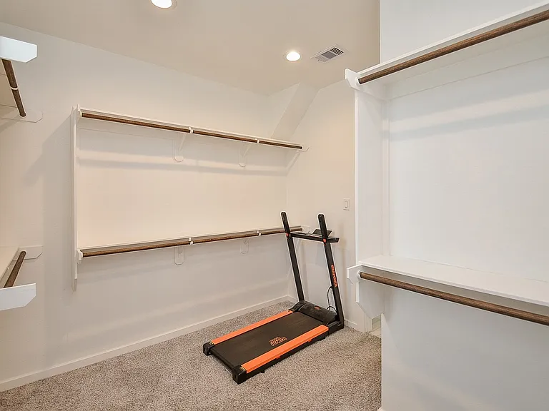 Primary/Master closet. Very spacious. For context, this picture shows a standard treadmill that fits in the closet with plenty of room left over.