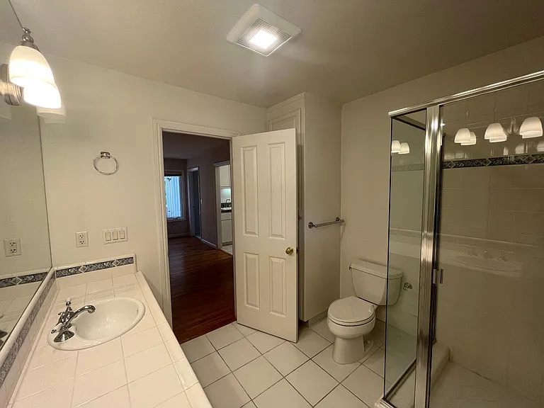 The hallway bathroom is well-appointed with dual sinks and a glass shower enclosure.