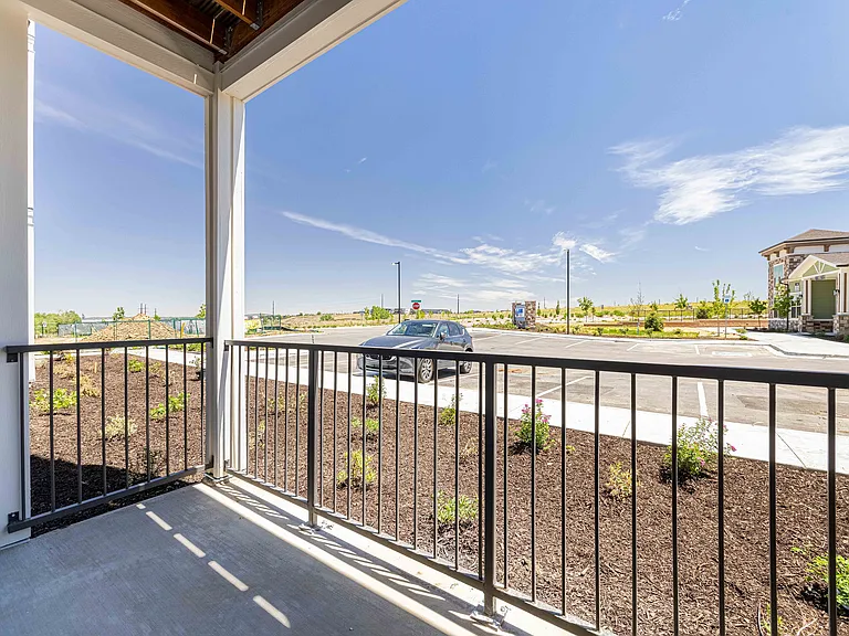 This private patio in the Garrett Parker A1 floor plan includes a covered overhang and metal railing overlooking the community's parking area.