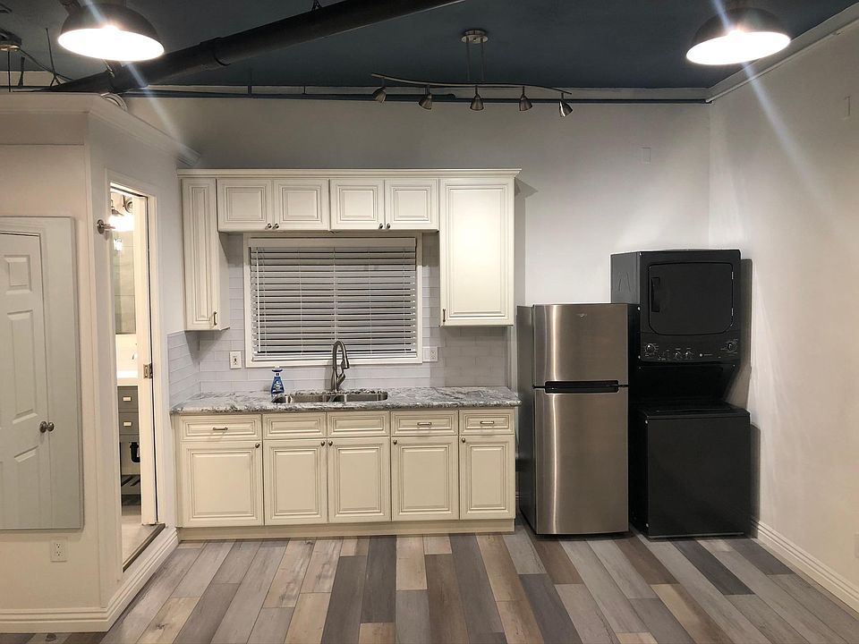 Living/Kitchen area with watrproof luxury vinyl plank flooring, SS refrigerator and W/D. 10Ft high ceilings in smoky blue with white walls. Urban light pendants and kitchen bar light all on dimmer switches.