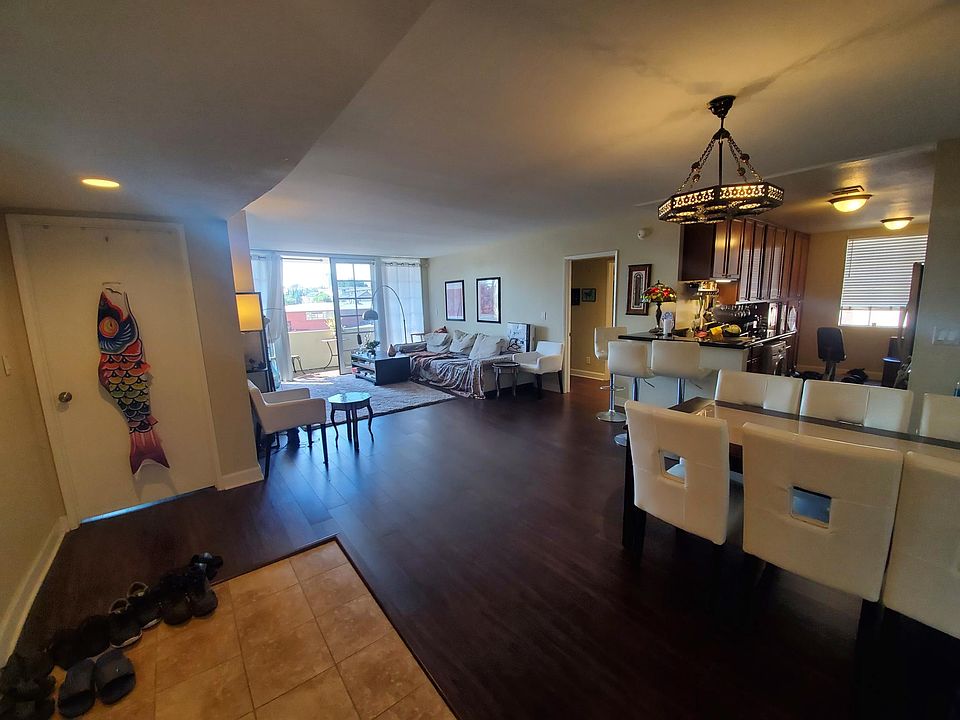 Living room from apartment entrance. Sunlit balcony that has nice breeze when door is open. Couch, coffee table, dining table, bar with bar seats.