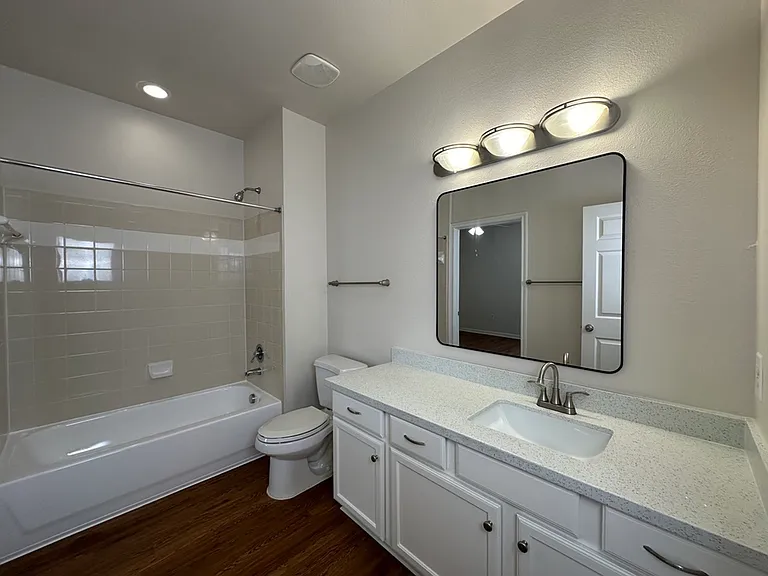 Elegant bathroom featuring a modern vanity, spacious mirror, and pristine bathtub with tile surround. Elegant bathroom featuring a modern vanity, spacious mirror, and pristine bathtub with tile surround.