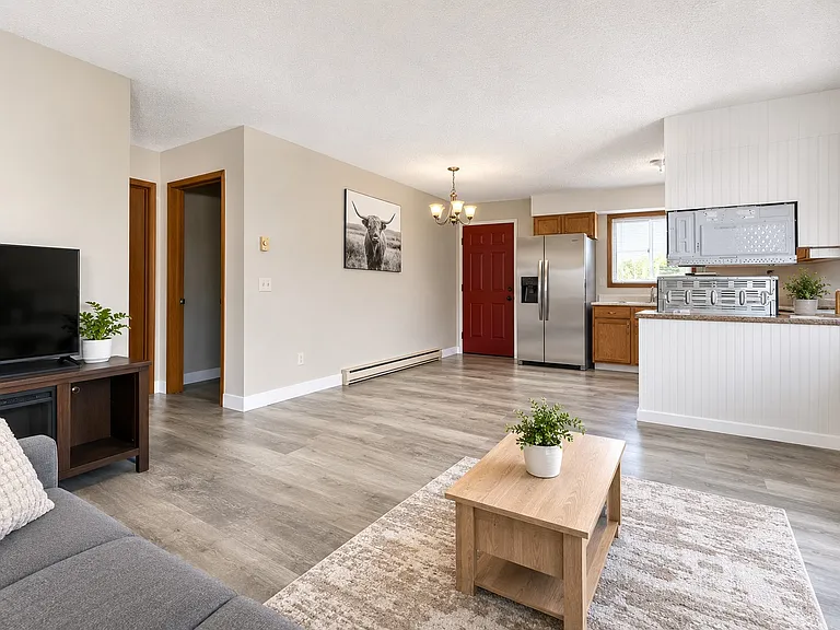 Bright open-concept living area featuring durable luxury vinyl plank flooring, abundant natural light, and a functional layout that flows seamlessly into the kitchen.
