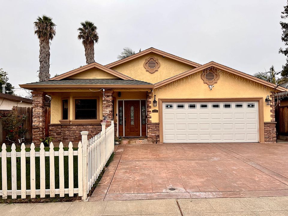 Beautiful house with decorative entrance door, rock veneer, stamped concrete driveway, green lawn and picket fence. Wifi controlled smart car garage door.