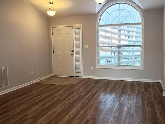 Living room with tile entrance, vaulted ceiling, ceiling fan, laminate flooring and faux wood blinds.