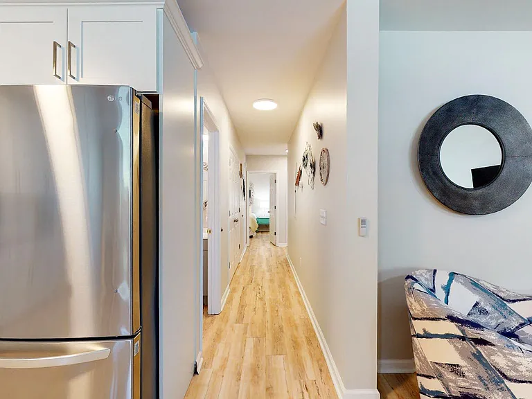 hallway to shared full bathroom, laundry closet and bedrooms