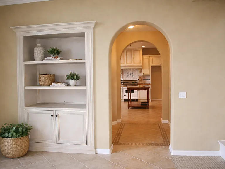 Architectural details including arched doorway and built in cabinetry enhancing flow between living areas